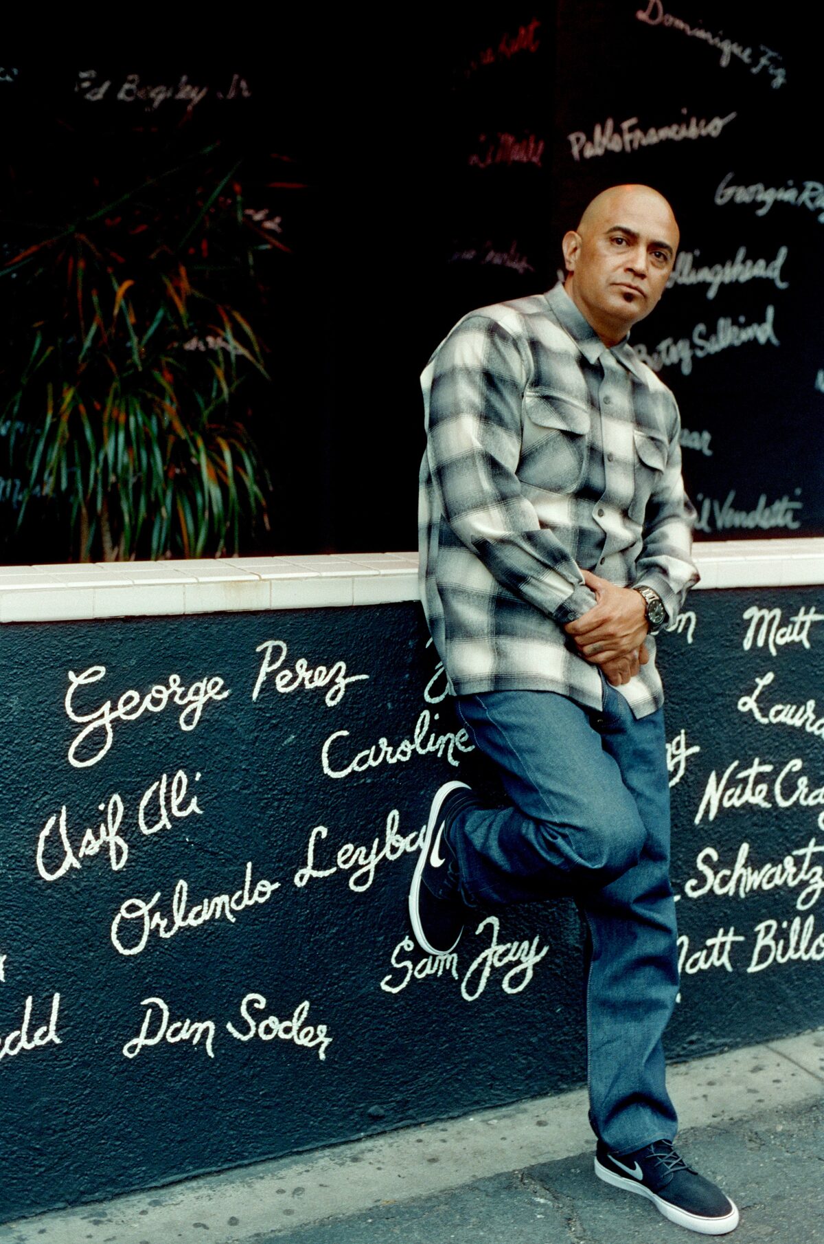 George Perez outside a comedy club, his name painted on the wall behind him